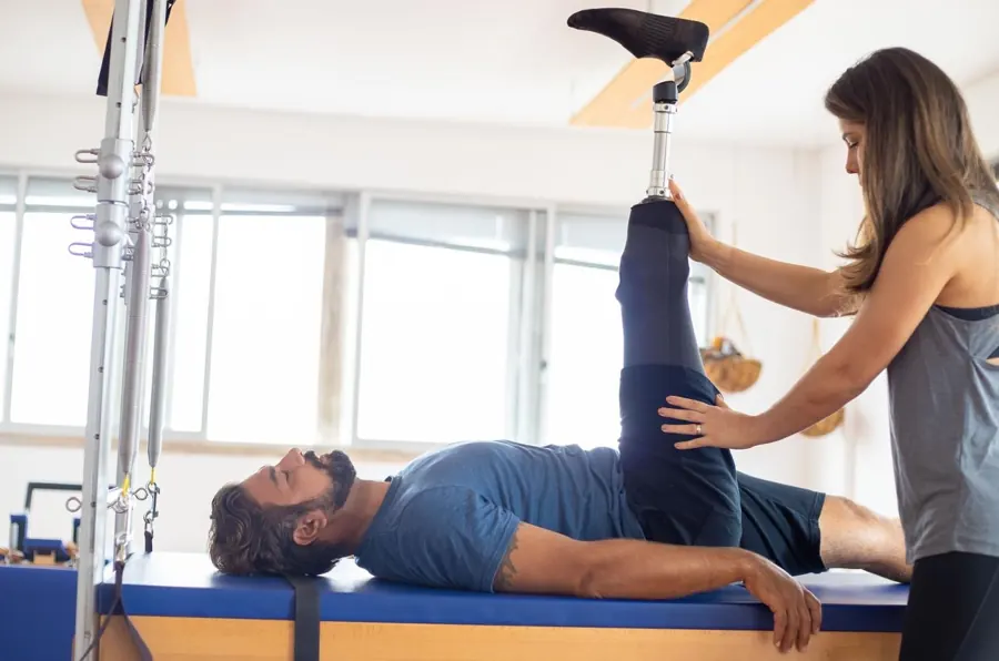 Kinesióloga trabajando la rehabilitación de la pierna de un paciente con prótesis